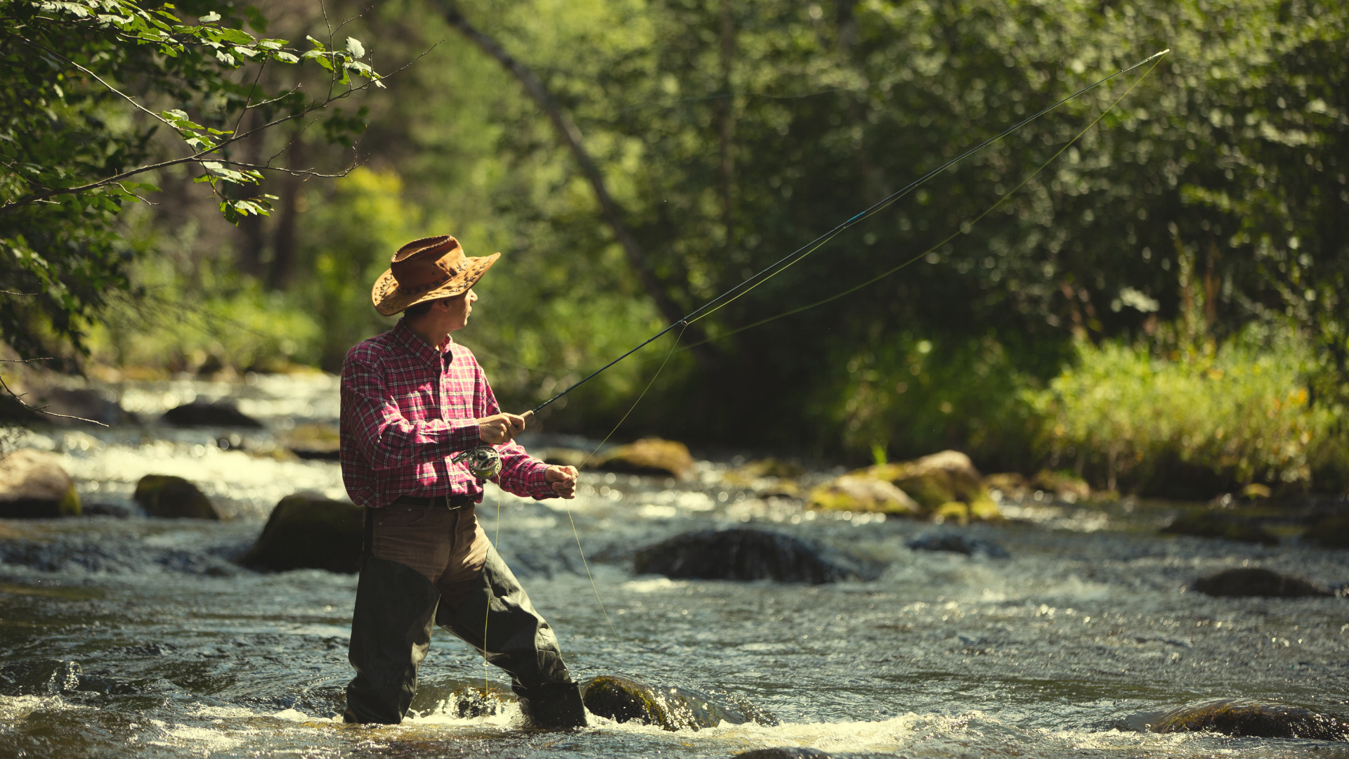 man fly fishing with hat in summer